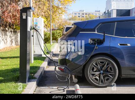 Almaty, Kasachstan - 11. November 2023: Der Ladestecker wird in einen BMW iX xDrive40 auf einem Parkplatz gesteckt. Stockfoto