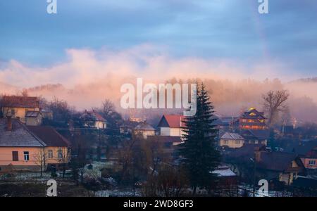 Ein ruhiges Dorf am Abend umgeben von dichten Bäumen und Nebel Stockfoto