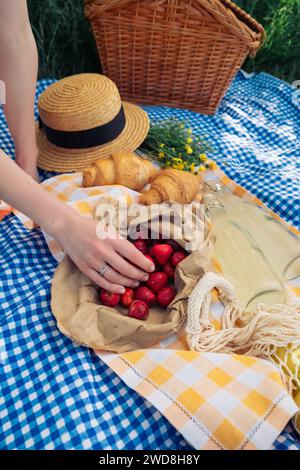 Die Hand einer Frau nimmt eine Erdbeere für ein Picknick in der Natur Stockfoto