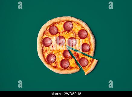 Blick von oben mit einer frisch gebackenen Pizza-Salami-Minimalist auf einem grünen Tisch. Stockfoto