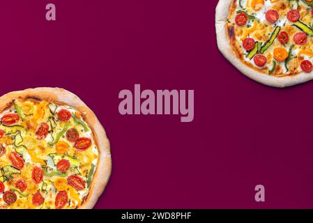 Blick über dem Zimmer mit zwei hausgemachten Pizzen, minimalistisch auf einem magentafarbenen Tisch Stockfoto
