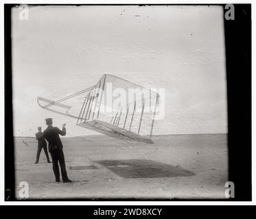 Geschichte der Luftfahrt - Wright Brothers - Seitenansicht des Segelflugzeugs, das als Drachen in Bodennähe fliegt, Wilbur links und Orville rechts, Segelflugzeug drehte sich vorwärts nach rechts und kippte nach unten, 1901 Stockfoto