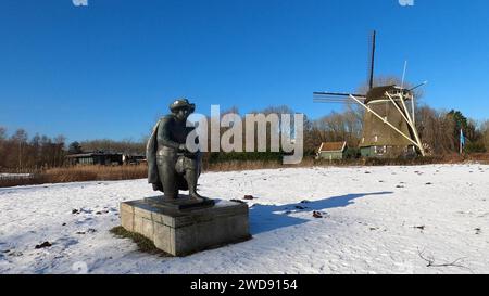 Amsterdam Niederlande 19. Januar 2024 Winterszenen in Amsterdam. Statue des niederländischen Malers Rembrandt van Rijn vor der Windmühle de Riekermolen entlang der Amstel mit Schneedecke und azurblauem Himmel. Schnee, Niesen, Weer, Wetter, Nässe, Standblende, schilder, Stockfoto