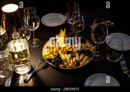 Elegantes Restaurant mit Käseplatte, umgeben von verschiedenen Glaswaren auf dem Tisch im Restaurant Stockfoto