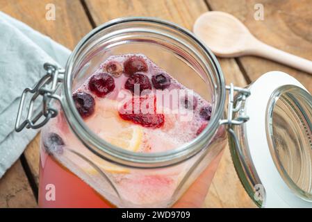 Hausgemachte fermentierte probiotische gesunde Wasserkefir mit Früchten - Vorbereitung in einem Glasgefäß auf Holztisch Stockfoto