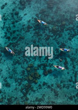 Blick von oben, atemberaubender Blick auf einige lange Boote, die auf einem türkisfarbenen Wasser schwimmen. Phuket, Thailand. Stockfoto