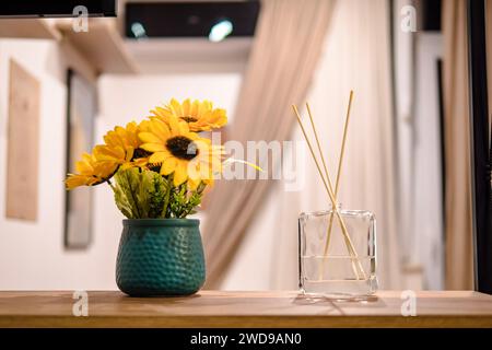 Nahaufnahme des Schilfdiffusors und des Hauses mit Kunstblumen auf Holzregal. Zimmererfrischer und Dekoration Stockfoto