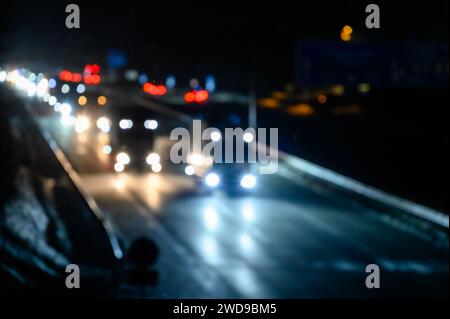 Verschwommener Straßenverkehr in der Nacht mit Bokeh-Effekt, abstrakter Hintergrund mit meist Lkws. Stockfoto