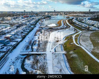 Dortmund, Nordrhein-Westfalen, Deutschland - Phoenix-See im Winter mit Schnee, vorne renaturierte Emscher. Der Fluss wurde zum naturnahem Gewaesser umgestaltet, Hochwasserschutz und Biodiversitaet durch neu gestaltete Ueberflutungsflaechen. Eine ehemalige Industriebrache von 99 Hektar Flaeche wurde zu Wohn-, Arbeits- und Freizeitflaechen und 24 Hektar Seeflaeche umgestaltet. Im Fall von Starkregenereignissen fungiert der See als Regenwasser-Rückhaltebecken. Die Emscher ist nach dem Bau eines parallel verlaufenden Abwasserkanals jetzt abwasserfrei, war vorher ein offener, oberirdischer Schmutz Stockfoto