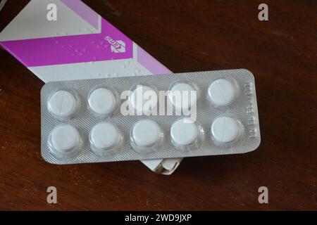 Medizin, Gesundheitswesen, Medikamente für Gesundheit und Prävention von Krankheiten. Große weiße Pillen in silberner Verpackung auf braunem Holzhintergrund. Stockfoto