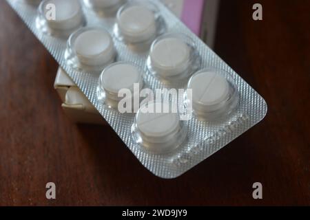 Medizin, Gesundheitswesen, Medikamente für Gesundheit und Prävention von Krankheiten. Große weiße Pillen in silberner Verpackung auf braunem Holzhintergrund. Stockfoto
