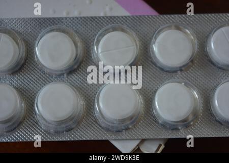 Medizin, Gesundheitswesen, Medikamente für Gesundheit und Prävention von Krankheiten. Große weiße Pillen in silberner Verpackung auf braunem Holzhintergrund. Stockfoto