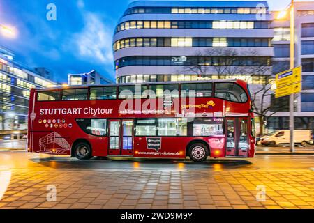 Stadtbesichtigung Stuttgart. Stadtrundfahrt im roten Doppeldecker. Innerstädtische Straße mit Fahrzeugen, moderne Architektur am Abend. Bewegungsunschärfe. // 17.01.2024: Stuttgart, Baden-Württemberg, Deutschland. *** Stuttgart CityTour City Tour in einer roten Doppeldeckerstraße mit Fahrzeugen, moderne Architektur am Abend Motion Blur 17 01 2024 Stuttgart, Baden Württemberg, Deutschland Stockfoto