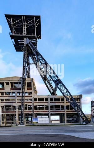 Stillgelegter Schachtturm des ehemaligen Kohlebergwerks Waterschei vor blauem Himmel, über dem Gebäude wird renoviert, niedrige Perspektive, sonniger Tag im Thor Park - H Stockfoto