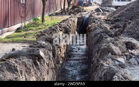 Erdarbeiten. Ein tiefer, langer Graben, der in den Boden gegraben wurde, um Kabel und Rohre zu verlegen. Telekommunikationsindustrie. Stockfoto