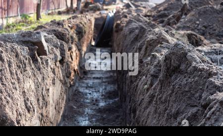 Erdarbeiten. Ein tiefer, langer Graben, der in den Boden gegraben wurde, um Kabel und Rohre zu verlegen. Stockfoto