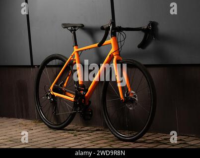 Schotterfahrrad. Glänzendes orangefarbenes Fahrrad für Offroad-Radfahren auf grauem Hintergrund. Nahaufnahme. Stockfoto