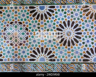 Alte islamische Fliesen (auch bekannt als zellige oder azulejos) mit traditionellen geometrischen Mustern schmücken eine Wand in der Alhambra, Andalusien, Spanien. Stockfoto