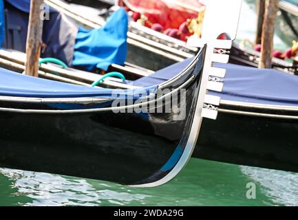 Metallischer Bug des Bootes, um Touristen nach Venedig in Italien zu transportieren, genannt Gondel, die auf dem Dock vertäut ist Stockfoto