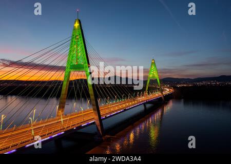 Aus der Vogelperspektive über die beleuchtete Megyeri-Brücke in einer seltenen weihnachtsdekoration mit atemberaubendem Sonnenuntergang im Hintergrund. Stockfoto