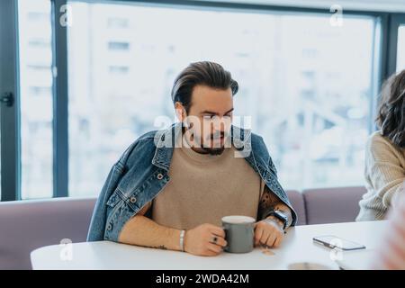 Nachdenklicher, gutaussehender männlicher Angestellter, der früh morgens einen Kaffee trinkt. Stockfoto