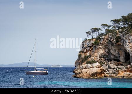 Ankeryacht in der Bucht von Portals Vells auf Mallorca. Kreuzfahrtschiff in der Ferne segelt im Mittelmeer. Urlaubsziel auf den Balearen Stockfoto