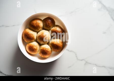 Burger-Brötchen oder Mini-Brötchen in der runden Backform. Sehr weich, frisch gebacken, hausgemacht, gebuttert. Weißer Marmorhintergrund. Minimalistisches Foto. Draufsicht Stockfoto