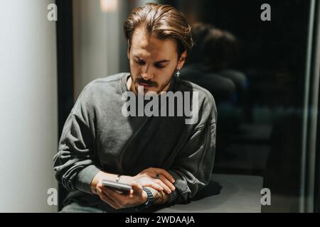 Männliche Person, die spät nachts im Büro Videoanrufe an einer schalldichten Telefonzelle hat. Stockfoto