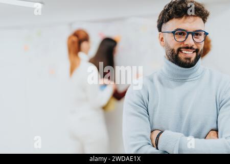 Gut aussehender Geschäftsmann posiert im Büro mit überkreuzten Händen und einem Lächeln im Gesicht. Kopierbereich. Stockfoto