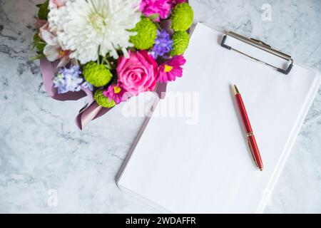 Strauß aus roten Rosen und ein Umschlag mit einer Notiz auf weißem Rücken Stockfoto
