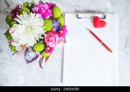 Strauß aus roten Rosen und ein Umschlag mit einer Notiz auf weißem Rücken Stockfoto