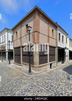 255 beigefarbenes Eckhaus im osmanischen Stil aus Putzmauerwerk auf dem Kopfsteinpflaster Rugica Jovan Spiro Kosturi im Alten Basar. Korca-Albanien. Stockfoto