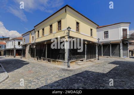 256 Gelbfarbenes Eckhaus im osmanischen Stil aus Putzmauerwerk auf dem Kopfsteinpflaster Rugica Jovan Spiro Kosturi im Alten Basar. Korca-Albanien. Stockfoto