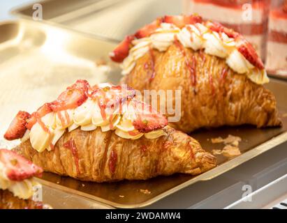 Das exquisit geformte Erdbeerbrot wird auf einem Stahlblech platziert, beleuchtet von warmen Lichtern und sieht sehr lecker aus. Stockfoto