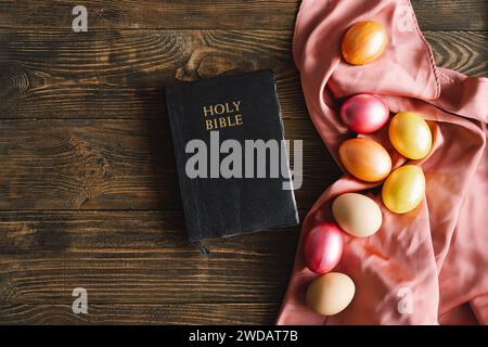 Bunte Ostereier und heilige Bibel auf hölzernem Hintergrund. Religionskonzepte Stockfoto