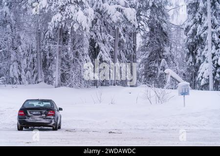 Das Auto parkte im Winter auf einem Parkplatz neben einem Wald Stockfoto