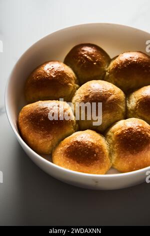 Burger-Brötchen oder Mini-Brötchen in der runden Backform. Sehr weich, frisch gebacken, hausgemacht, gebuttert. Weißer Marmorhintergrund. Minimalistisches Foto Stockfoto