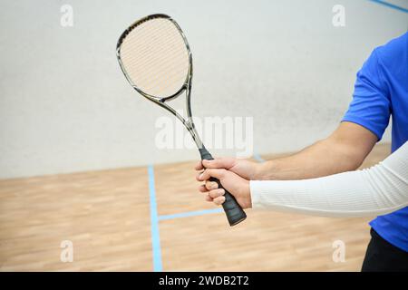 Unerkennbarer Mann, der der Frau beibringt, Squashschläger richtig zu halten Stockfoto