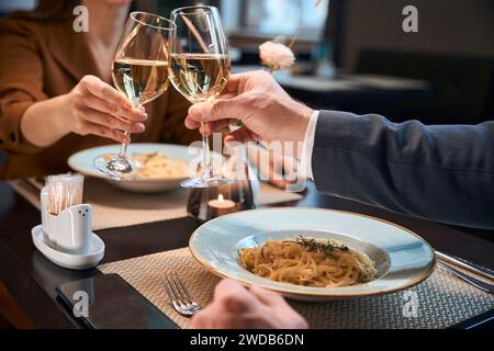 Teilbild eines Paares, das Wein aus Gläsern im Hotelrestaurant toast Stockfoto