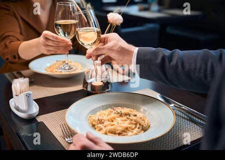 Zugeschnittenes Bild eines Paares, das Wein aus Gläsern im Hotelrestaurant trinkt Stockfoto