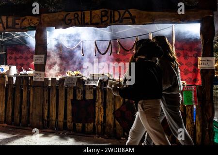 Zakopane, Polen, 19. Januar 2024. Frauen kommen an einem Stand mit gegrillten Würstchen auf einer berühmten Krupowki-Straße im Zentrum von Zakopane vorbei, einem beliebten Ferienort in den Bergen der Tatra. Die Schulhalbzeit begann vor einer Woche. Quelle: Dominika Zarzycka/Alamy Live News Stockfoto