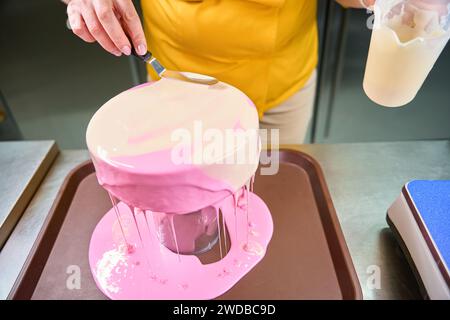 Ein professioneller Bäcker verwendet in der Backküche Zuckerguss auf das Dessert Stockfoto