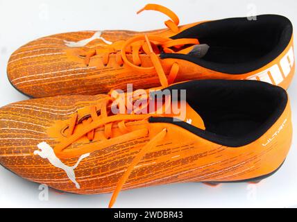 Dublin, Irland - 13. Februar 2024: Ein Foto von orangen PUMA Kids Ultra 4,1 Fußballschuhen auf weißer Oberfläche. Stockfoto