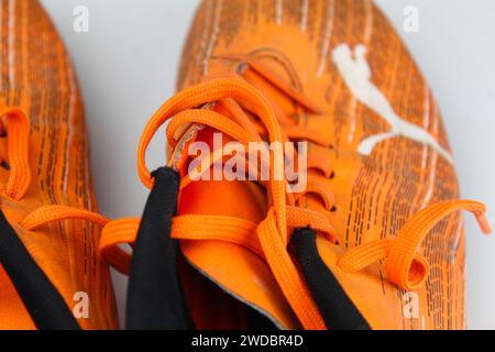 Dublin, Irland - 13. Februar 2024: Ein Foto von orangen PUMA Kids Ultra 4,1 Fußballschuhen auf weißer Oberfläche. Stockfoto