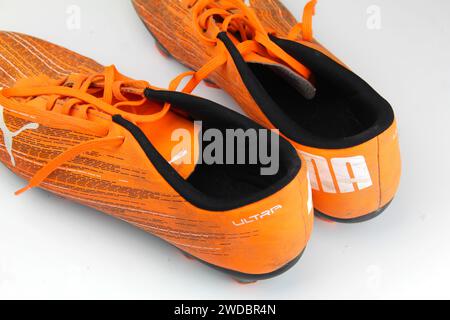 Dublin, Irland - 13. Februar 2024: Ein Foto von orangen PUMA Kids Ultra 4,1 Fußballschuhen auf weißer Oberfläche. Stockfoto