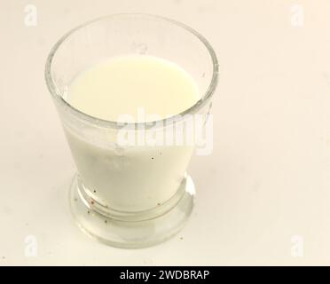 Ein Foto von einem Glas Milch auf einer weißen Oberfläche. Stockfoto