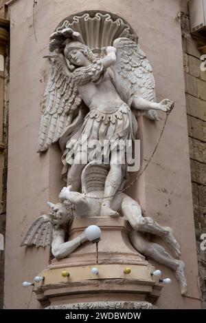 Der Heilige Michael der Erzengel tötet den Teufel, der zu seinen Füßen liegt. Statue Fries auf Gebäuden. Valletta, Malta 2024 2020er Jahre HOMER SYKES Stockfoto