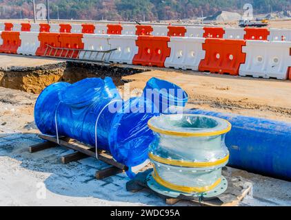 Industrielle Metallrohre, die auf dem Boden vor orangefarbenen und weißen Kunststoffbarrieren auf einer Wohnbaustelle in Südkorea und Südkorea verlegt werden Stockfoto