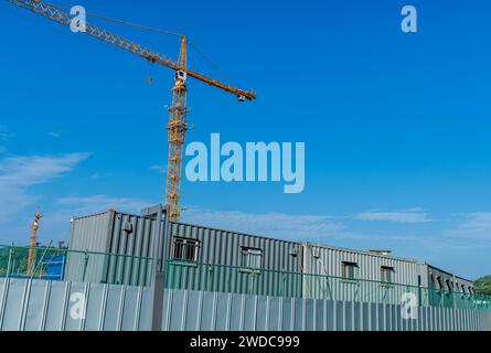 Graue Metallgebäude hinter Zaun mit Baukran vor blauem Himmel im Hintergrund, Südkorea, Südkorea, Südkorea Stockfoto