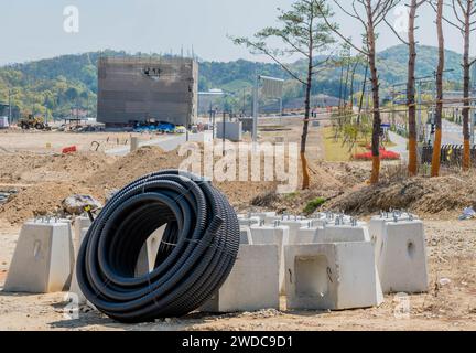 Daejeon, Südkorea, 18. April 2021: Große Rolle flexibler PVC-Rohre, die an Betonstützen für Laternenpfosten auf der Baustelle, Südkorea, gelehnt ist Stockfoto